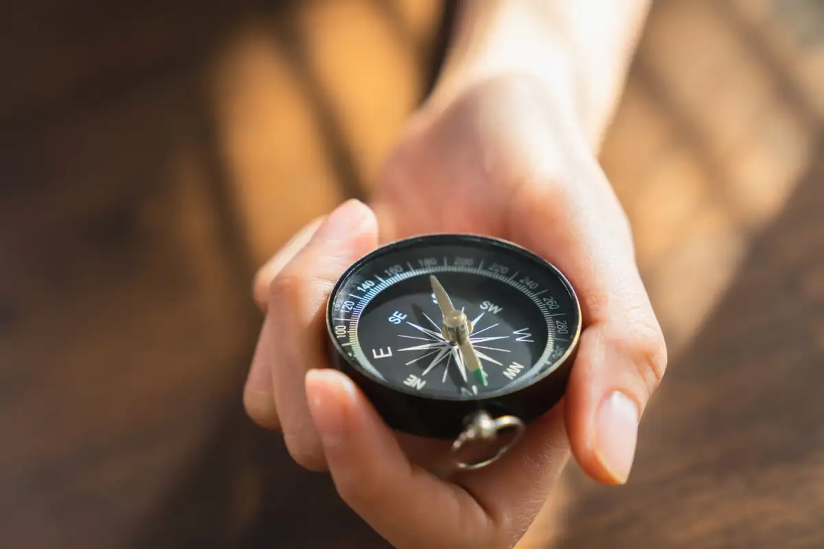 A hand holding a compass pointed toward light, representing internal guidance.